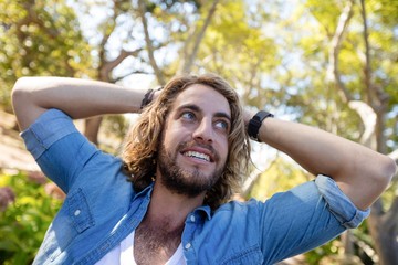 Happy man standing with hands behind head 