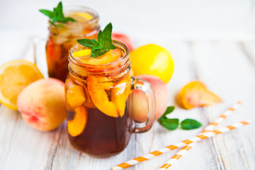 Homemade lemonade with ripe  peaches and fresh mint. Fresh peach ice tea on white wood table. Copy space background.
