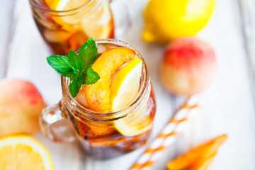 Homemade lemonade with ripe  peaches and fresh mint. Fresh peach ice tea on white wood table. Copy space background.