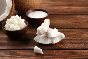 Coconut and bowls with fresh oil on wooden background