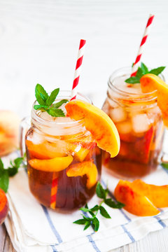 Homemade lemonade with ripe  peaches and fresh mint. Fresh peach ice tea on white wood table. Copy space background.