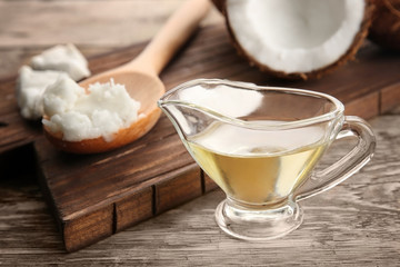 Coconut and kitchenware with fresh oil on wooden board