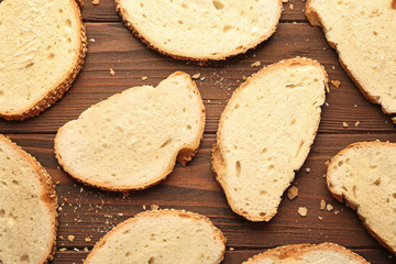 Slices and crumbs of wheaten bread on wooden background