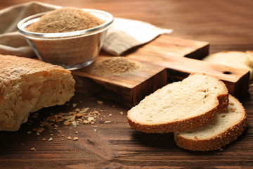 Glass bowl of bread crumbs and broken loaf on wooden table