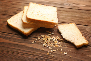 Slices and crumbs of wheaten bread on wooden background