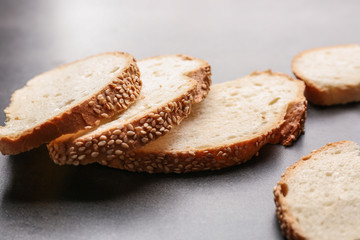 Slices and crumbs of wheaten bread with sesame seeds on grey background