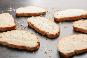 Slices and crumbs of wheaten bread with sesame seeds on grey background