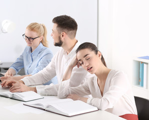 Fototapeta premium Tired young woman sleeping during conference in office