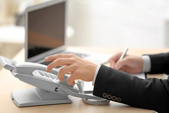 Man picking up telephone receiver while working in office