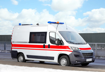 Modern ambulance car on road near construction site