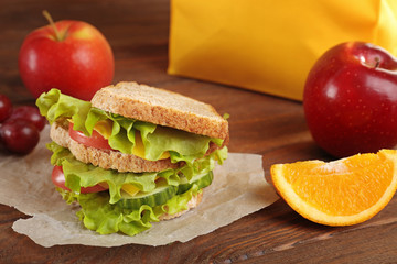 Delicious sandwich and fresh fruits on wooden background