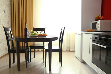 Modern interior of kitchen room with large shiny window and wooden round table