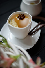 Hot tea with cardamom and lime over rustic black wooden background