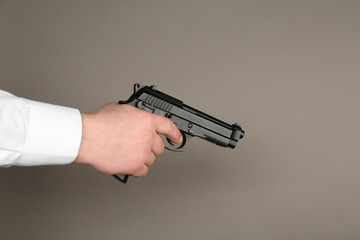 Man's hand holding gun on color background