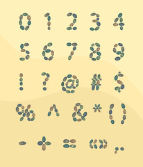Numbers and symbols lined with stones on a background of sand.