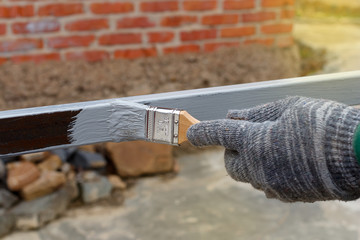 Gloved hand painting primer anti rust on steel poles for construction. Half - painted surface. Smear of paint brush.