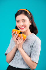 Healthy food. Smiling lovely pinup asian girl holding orange over blue background.