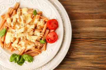 Portion of delicious pasta with cheese on wooden background