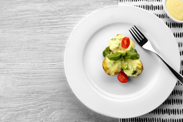 Plate of delicious baked potato with cheese sauce on white wooden background