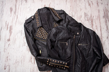 Fashionable concept. Two black leather jackets on a wooden background. Top view, space for text