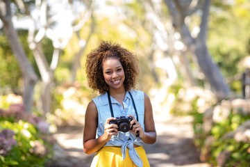 Smiling woman standing with digital camera