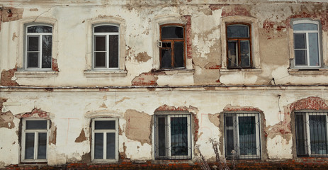 Fototapeta na wymiar Background, texture, an old abandoned building. Wall with crumbling plaster and paint, Windows