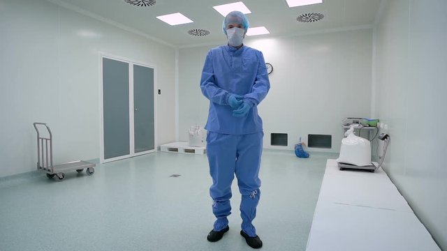 A man working in a clean room, pharmaceutical enterprise. Specialist in a protective suit, gloves, glasses and a mask.