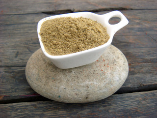 Coriander powder filled bowl on rounded stone