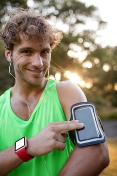 Smiling jogger listening to music from mobile phone