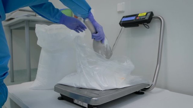 Pharmaceutical production. Working Party forms a chemical ingredient by weight makes for a drug. White powder is poured into a bag on electronic scales.
