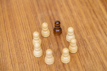 Weiße Schachfiguren und eine schwarze im Kreis angeordnet. Symbol für Inklusion und Miteinander