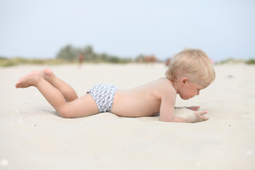 A little boy is lying on the sand