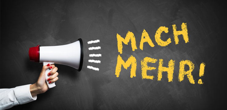 Hand hält Megafon mit Slogan "Mach mehr!" auf Kreidetafel