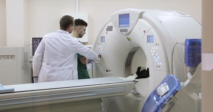 4K Two Doctors presses settings button of CT MRI scanner.
