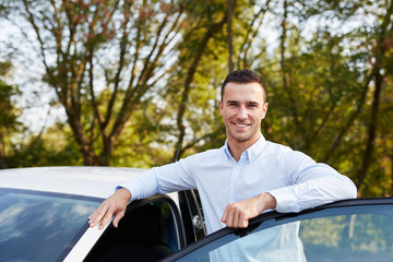 Smiling man standing and leaning on car door
