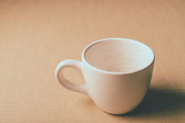 Empty white cup on wooden table background.