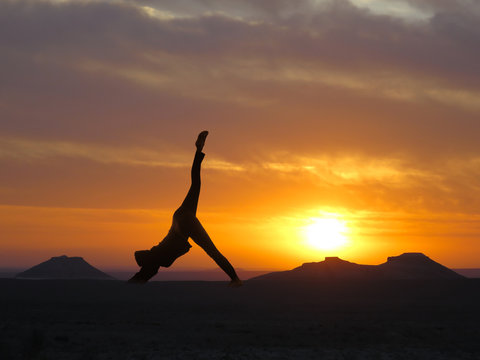 Girl practicing yoga on a background of mountains and sunset