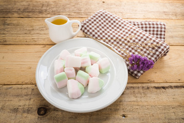 Marshmallows in white dish on wooden background.