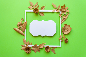 Vintage square frame with craft paper flowers on the green background. Flat lay. Nature concept