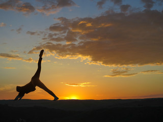 Girl practicing yoga on a background of mountains and sunset