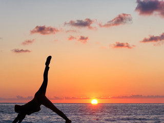 Girl practicing yoga against the background of the ocean and sunset.
