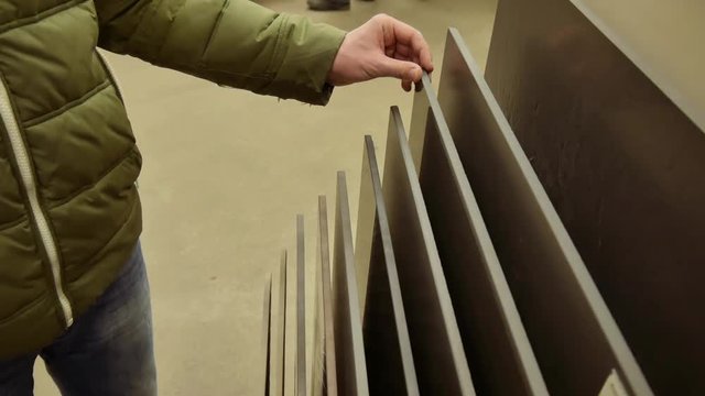 Young man selecting floor tile in a hardware store or warehouse close up