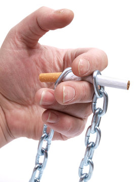Cigarettes and hand with chain on white background