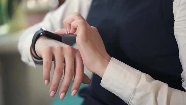 Close up shot of the manager's hands, who uses a smart watches to work. A woman can respond to incoming messages with smart watches that come on the smartphone.