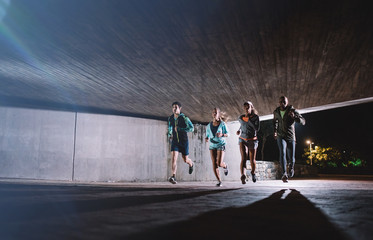 Group of young people running together at night