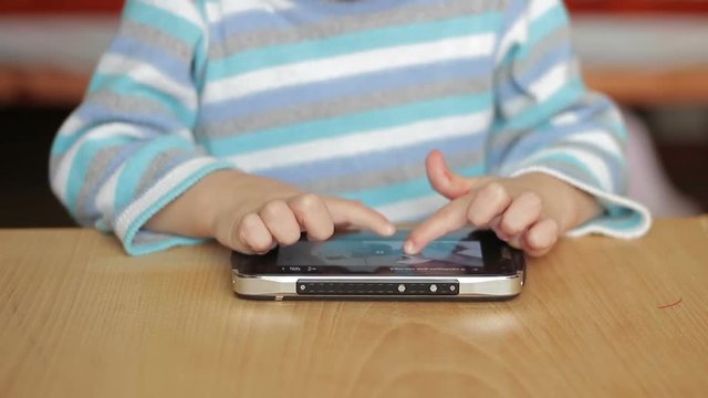 Hands of a child playing with a smartphone
