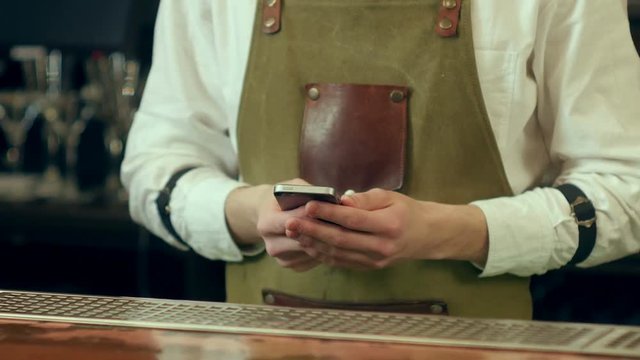 Barman hands text message using mobile phone