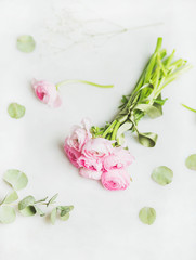 Light pink spring ranunkulus flowers bouquet on white marble background, top view, selective focus, copy space. Spring greeting card concept