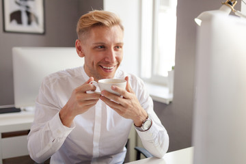 Cheerful office employee with coffee cup