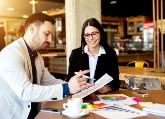 Colleagues working on charts and graphs looking glad having success.